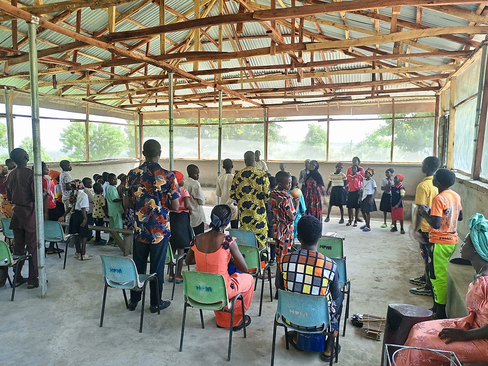 People seated in an open-sided hall during a group teaching session.