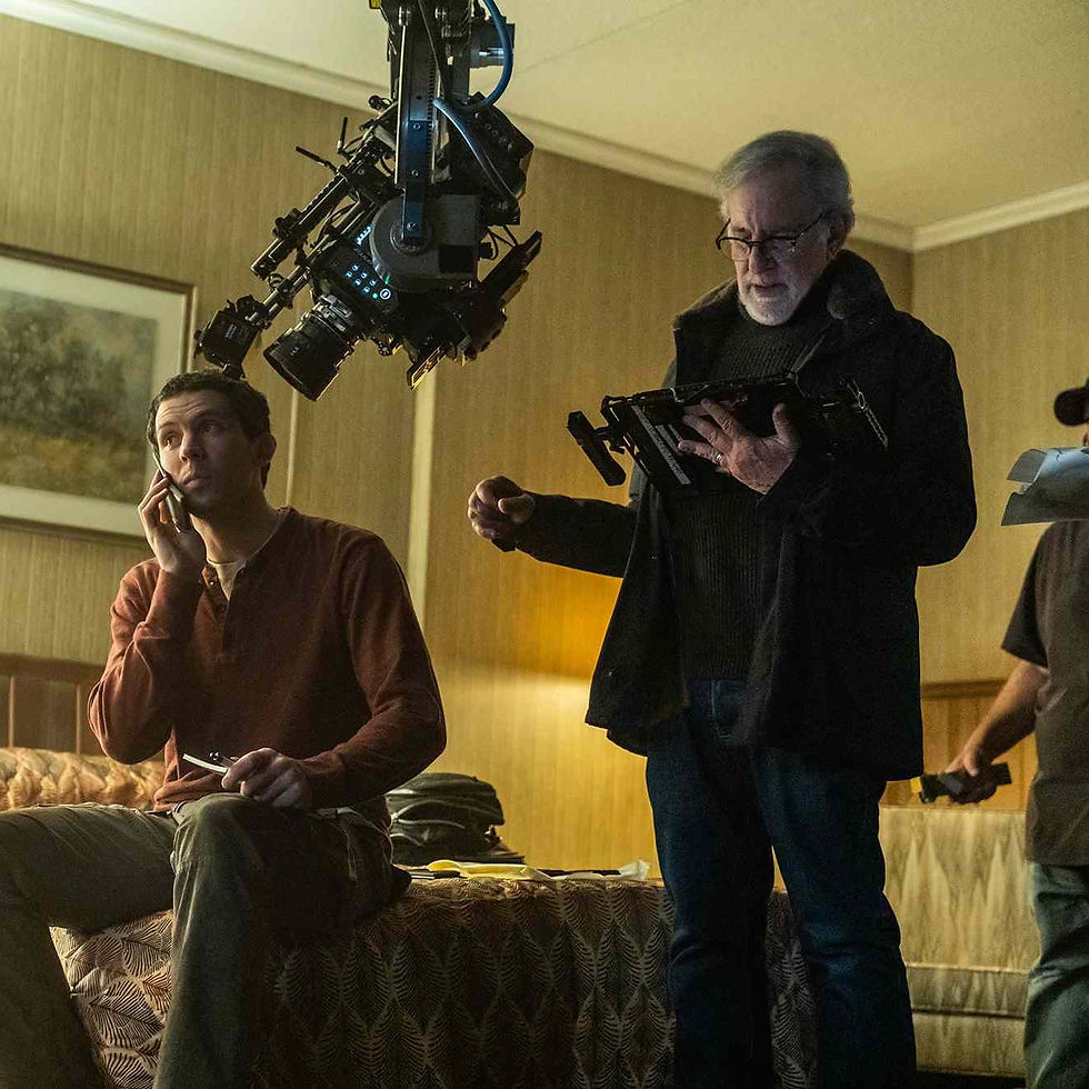 Behind-the-scenes shot from Disclosure Day showing a man on the phone in a motel room while an older director stands beside a massive camera rig, basically staging the exact type of white-people-with-classified-information anxiety the article is talking about.