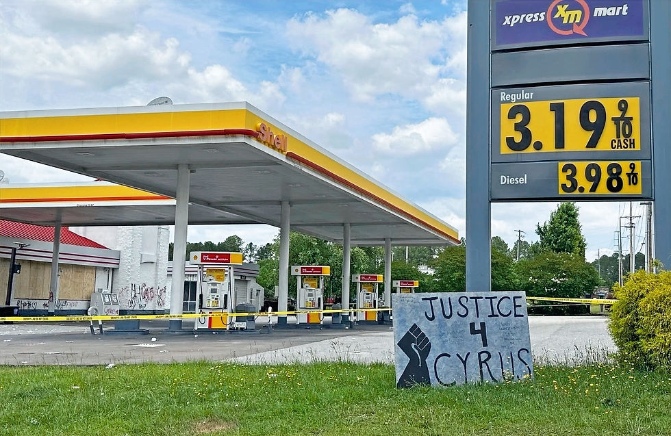Exterior view near a gas station associated with a fatal shooting investigation, showing a public memorial or protest sign reading “Justice 4 Caleb” placed in the area. The image reflects community response and calls for justice following a violent incident.