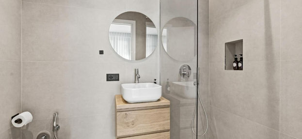 Modern bathroom with toilet, wood vanity, and glass shower