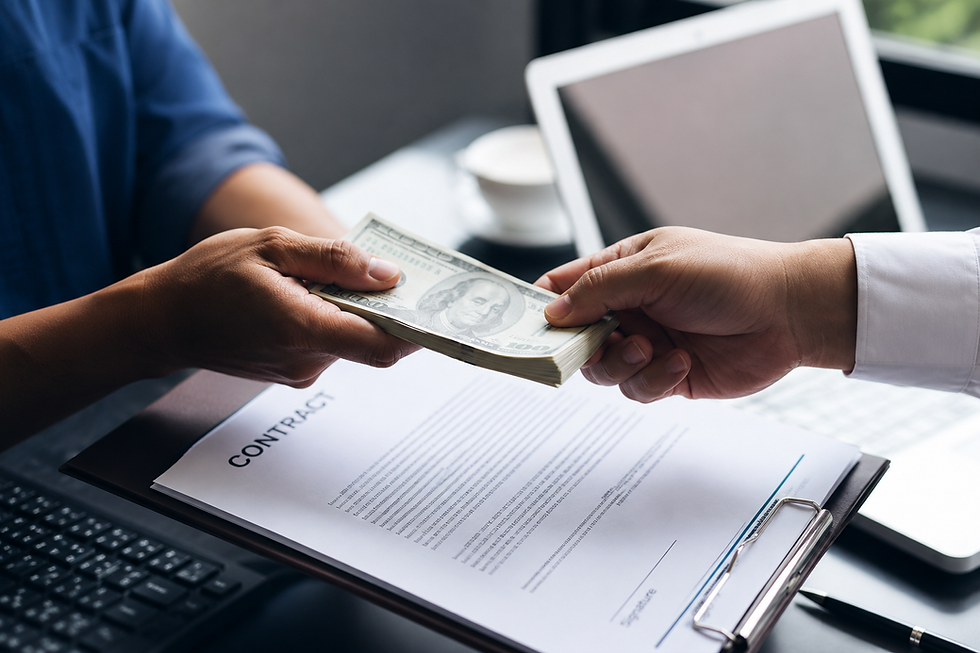 Hands exchanging a stack of cash over a signed contract.