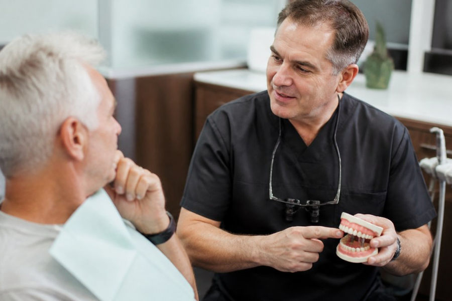 Dentist explaining a treatment plan for full mouth implants vs traditional dentures to a patient