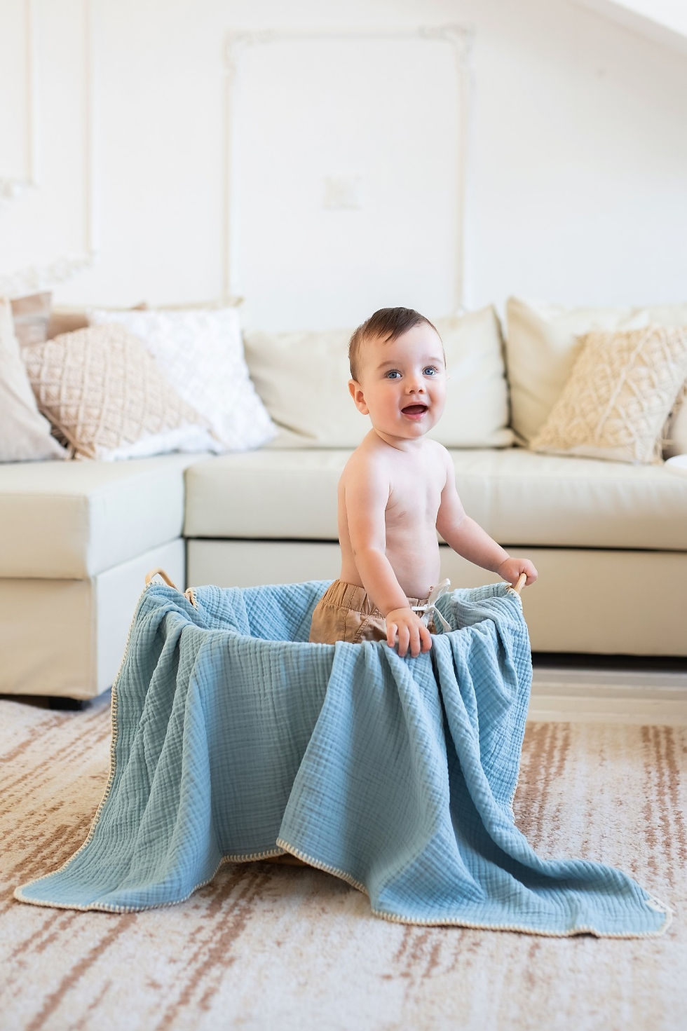 Thumbnail: Baby with a Caline baby muslin blanket standing in a basket.