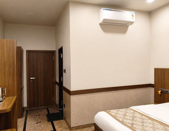 Interior view of Deluxe Room with air conditioning and modern furnishings at Hotel Rajdeep Mount Abu.