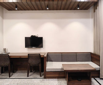 Super Deluxe Room featuring sofa-cum-bed, work desk and seating area at Hotel Rajdeep Mount Abu.