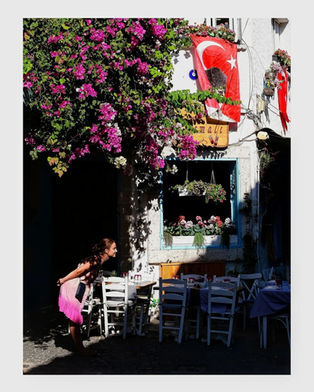 Woman in pink admires bougainvillea flowers, Turkish flag, outdoor cafe.