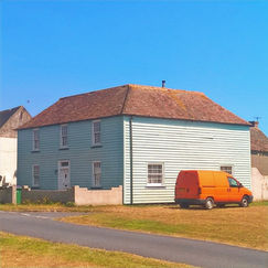 Light blue house with brown roof and orange van parked nearby.
