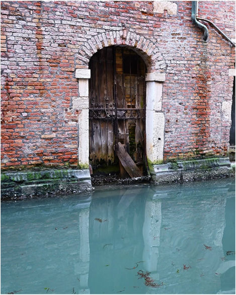 Arched wooden door entrance at water level in brick building