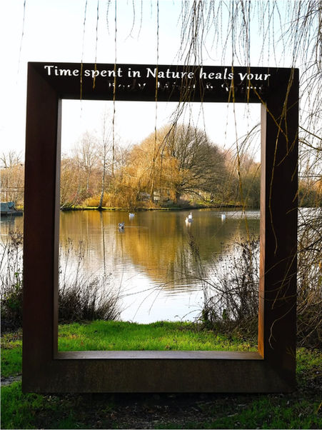 Metal frame with "Time spent in Nature heals your" overlooking calm lake.