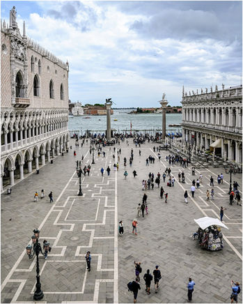 Historic St. Mark's Square bustling with people, columns, and distant lagoon.