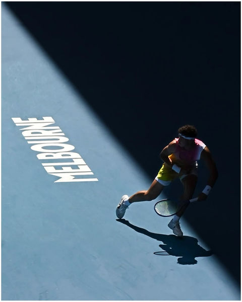 Tennis player on court, "MELBOURNE" text lit by spotlight.