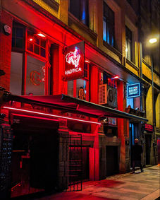 Night scene, GORY LIVERPOOL bar building, bright red neon lighting.