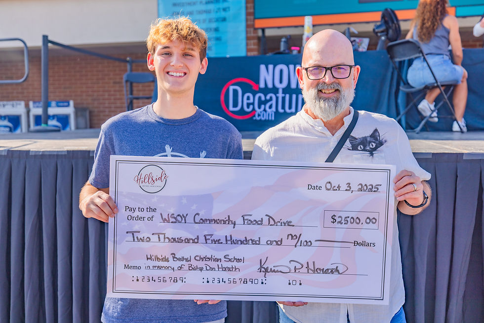 Two people posing with a donation check in front of a stage