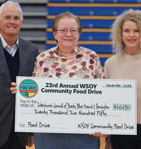 Three people smile while holding a large ceremonial check for $20,250 at the 23rd Annual WSOY Community Food Drive. The setti