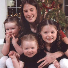 Kelsey smiling with the three young girls she nannied, close together and looking happy, capturing the bond they shared.