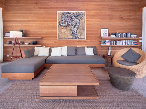 Experience seamless harmony in The Pines Villa's living pavilion. With high wooden vaulted ceilings and tall sliding glass doors, this open-plan lounge embraces the sea and pool views from all angles. Opt for air-conditioned comfort or relish the island spirit of indoor-outdoor living. Sink into the inviting sofa seating while gazing at the open kitchen on the other side. The long breakfast bar lined with stools and the remarkable wooden dining table at the heart of the room complete the symphony of luxury and nature. #LuxuryIslandLiving #SeamlessHarmony