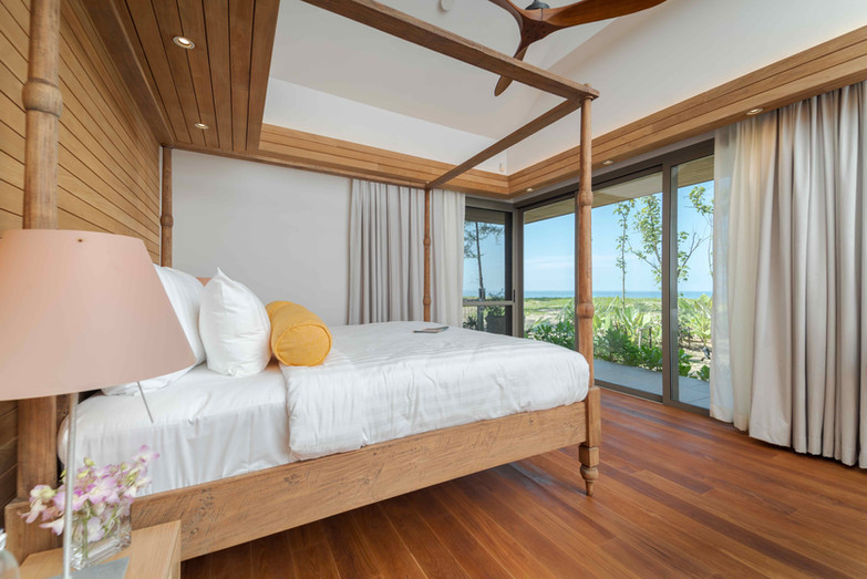 Oceanview Phuket villa bedroom with four-poster bed and wooden floor.
