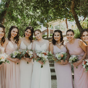 bride with bridesmaids standing in shade of tree