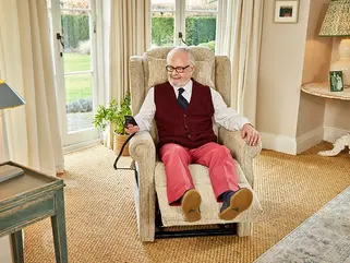 An older smartly dressed gentleman sat in a arm chair reclining his feet