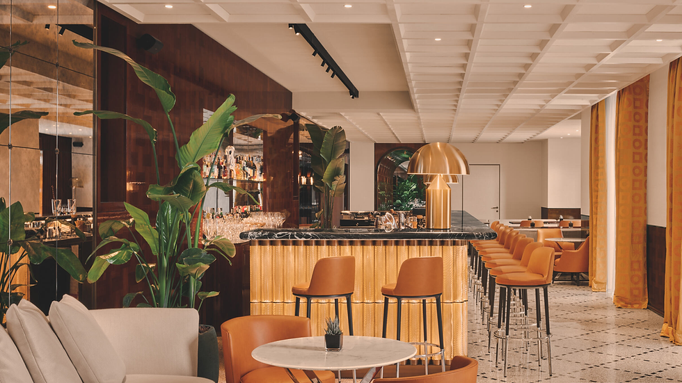 Stylish bar interior with orange chairs, plants, and a reflective counter under warm lighting. Marble floor and patterned curtains enhance elegance.
