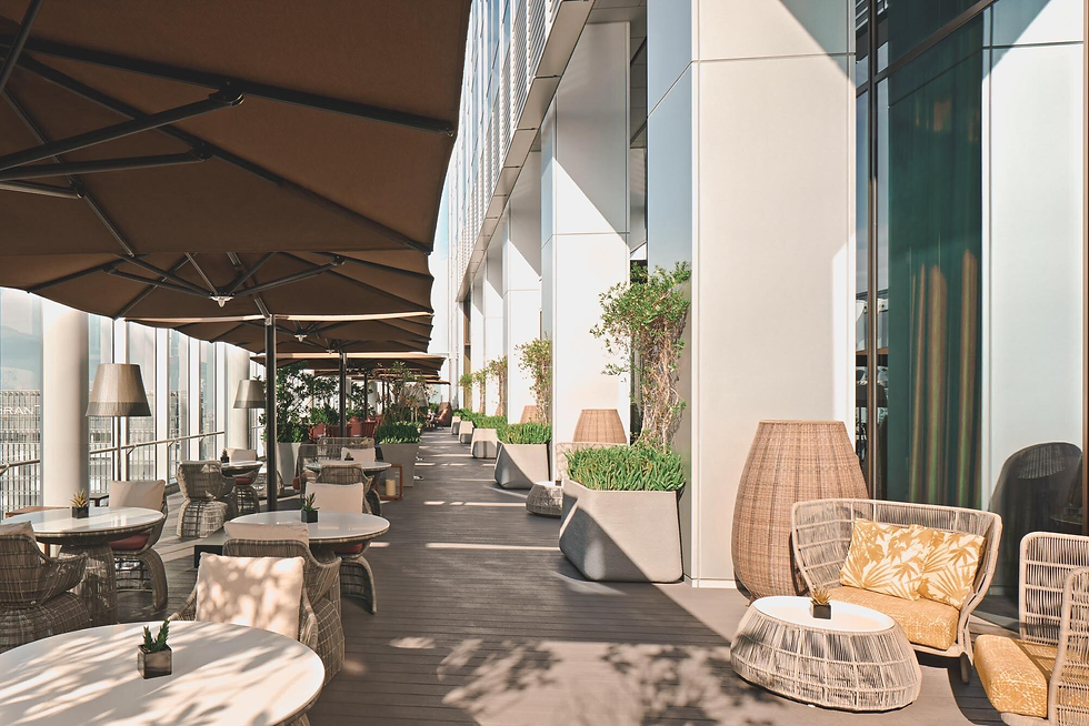 Rooftop terrace with brown umbrellas, wicker furniture, and potted plants. Tables set for a relaxed outdoor dining atmosphere.