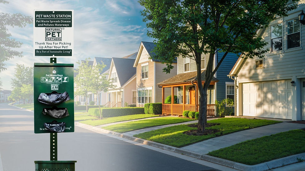 Pet waste station with green bag dispenser near suburban homes under a clear sky. Sign encourages pet waste cleanup for sustainability.