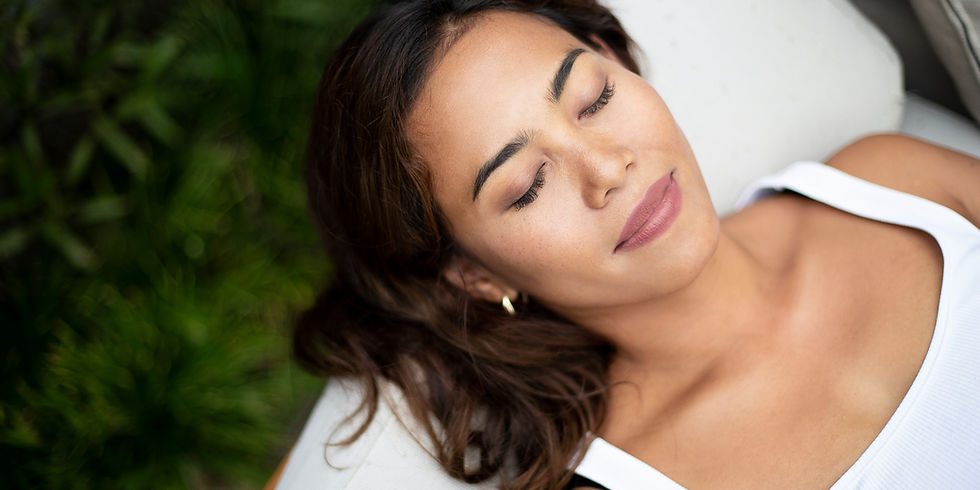A lady lying face-up with her eyes closed, meditating
