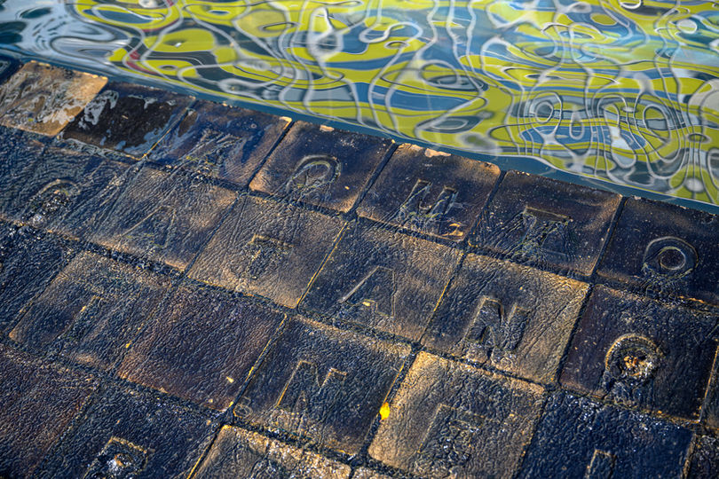 Image of water flowing over handmade tiles with letters embedded on them.
