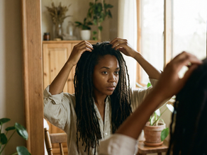 Femme noire regardant ses locks dans un miroir, cheveux locksés naturels, vérification de l’hydratation des locks