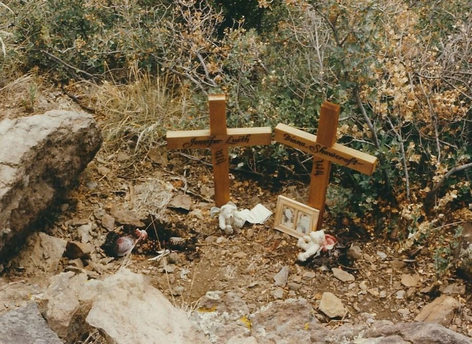 Desert memorial site with hand-engraved crosses and picture frame.