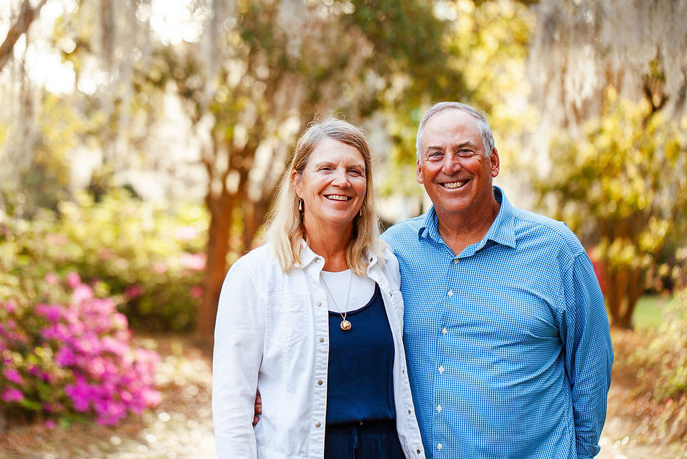 A couple standing on a dirt path under the oak trees.