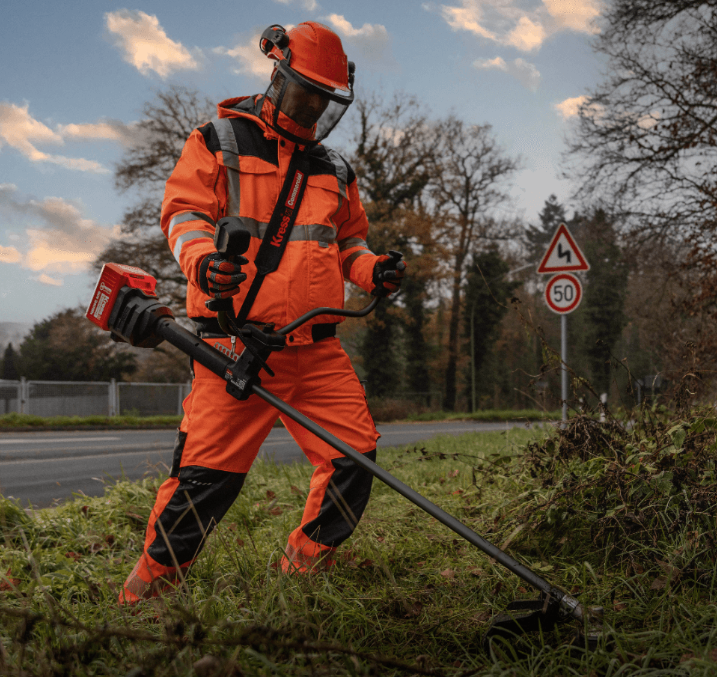 A road maintenance crew member using a heavy-duty commercial trimmer to tackle tough outdoor tasks, highlighting the durability and cost-efficiency of the tool.