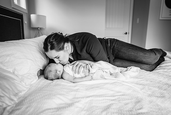 Newborn baby laying on bed with mom for lifestyle photography in Penticton
