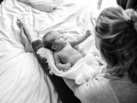postpartum mother with newborn on a cozy bed