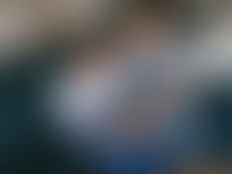 a family is sitting on the sofa for an in-home newborn photography session with their baby boy.