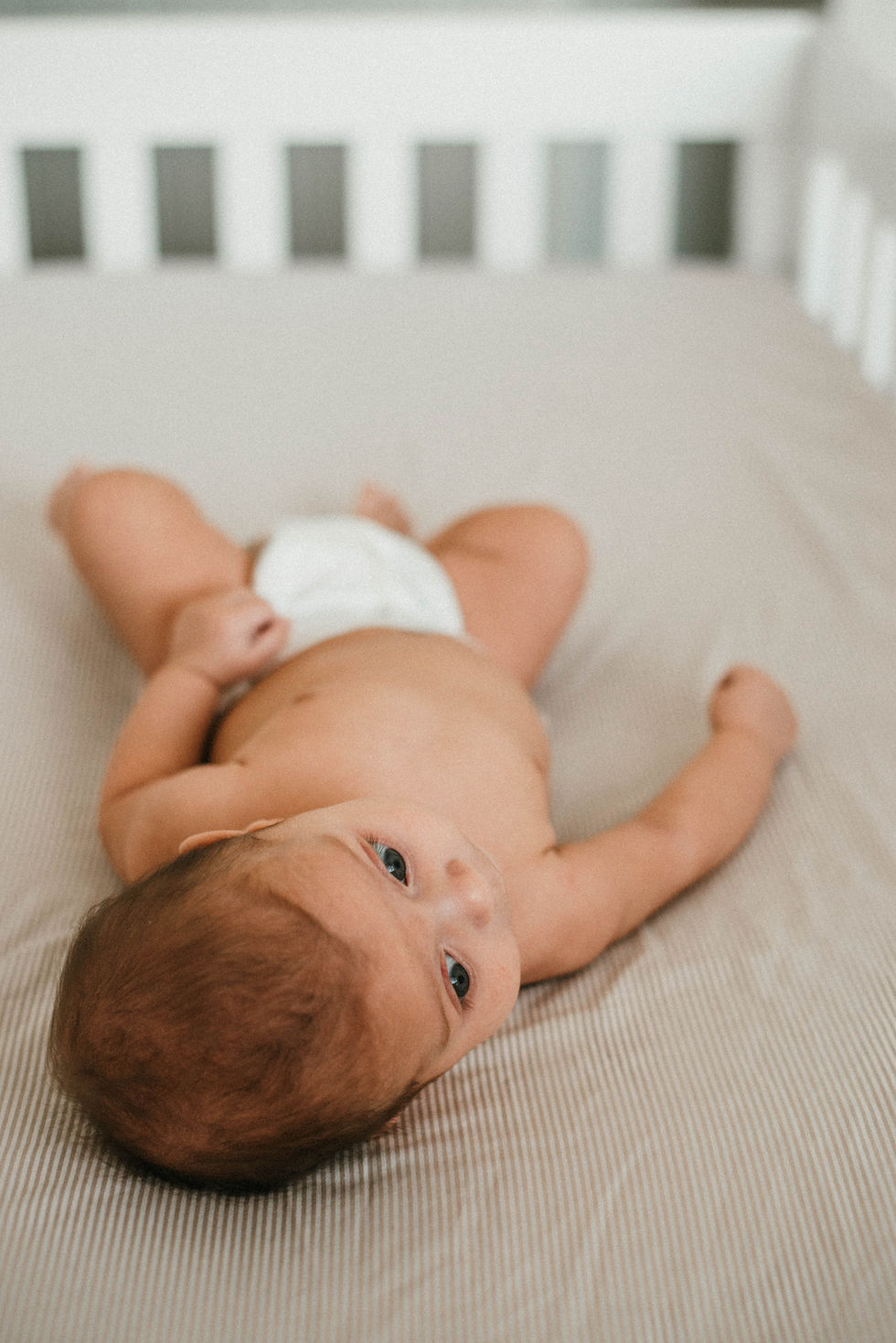 Close-up view of a newborn baby wrapped in a soft blanket on a beach towel
