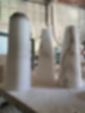 Two alabaster cones sitting on a dusty table in an Italian workshop.