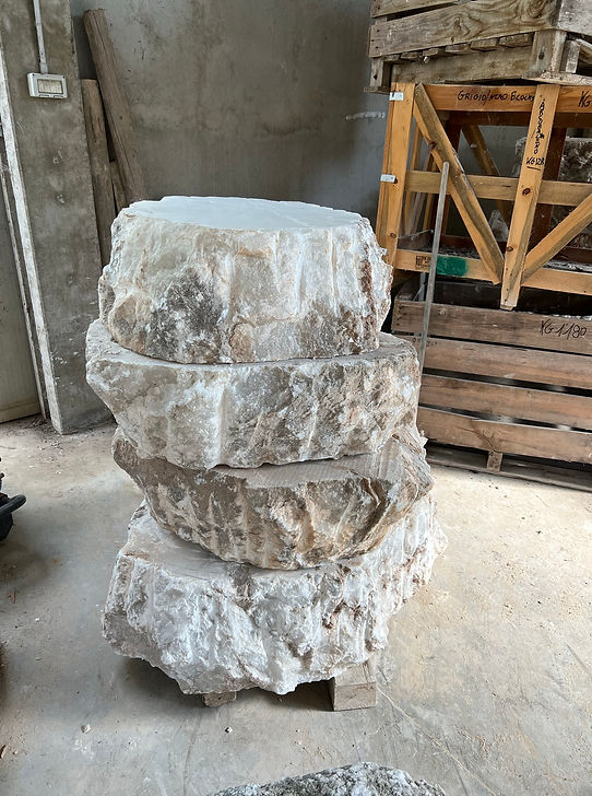 Large stacked slabs of alabaster in a concrete warehouse.