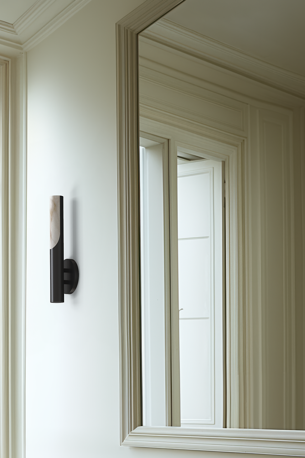 Thumbnail: A white Parisian bathroom with a rectangular stone sink and a mirror, showcasing a cylindrical blackened brass and alabaster sconce next to the window. Detail shot 2