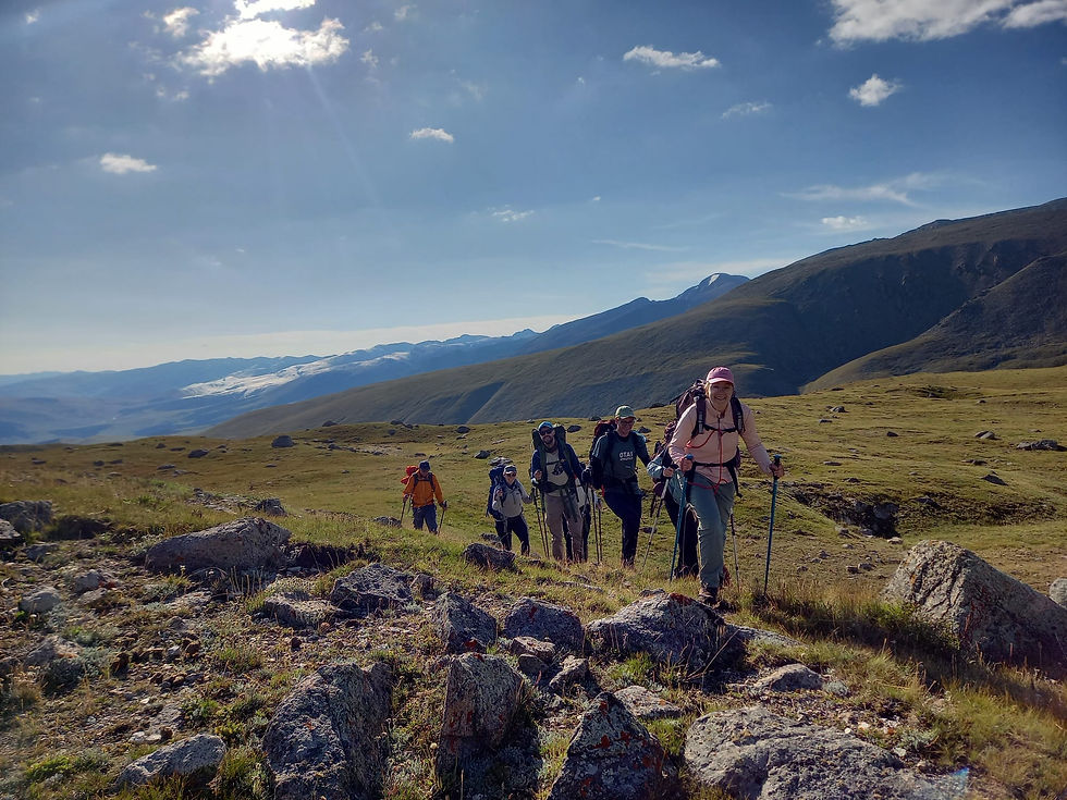 Groep hikers wandelt in glooiend groen berglandschap in Kazachstan op een zonnige dag