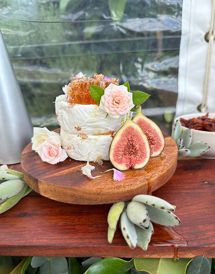 a large while of cheese decorated with figs and flowers