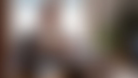 Man in a gray outfit sits in a chair with closed eyes, hands on stomach, beside a laptop. Sunlit room with plants, calm atmosphere. How Early Year Stress Impacts Your Gut and Emotional Balance.