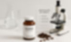 Clove supplement bottle with cloves, microscope, and purity certificate. Beakers in the background on a white surface create a clinical mood.