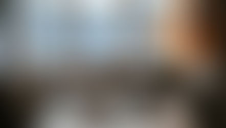 Cozy dining area with steaming coffee, cereal bowls, and a pastry on a wooden table. Snowy view outside, warm lamp and candles inside.