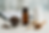 Glass bowl of cloves, brown bottle, white jar, capsules, and a wooden spoon with powder on a white table. Clipboard in blurred background. Herbpy Blog. Herbpy supplement