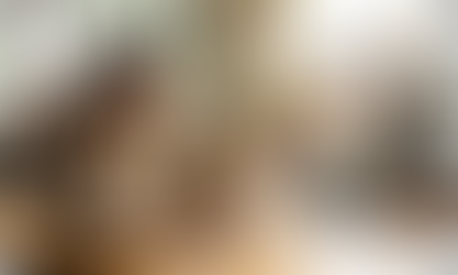 A professional woman working calmly at a laptop in a busy coffee shop, with a bottle of KSM-66 on the table.