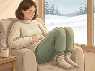 Woman in a cozy sweater relaxes in an armchair, holding her belly. A snowy landscape is visible outside the window. Warm, serene mood.