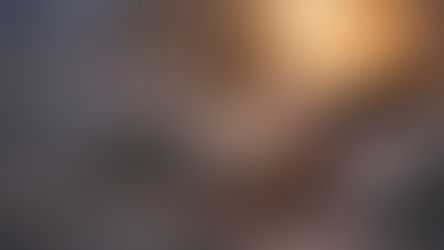 Person sleeping in bed under white covers, soft light from a bedside lamp, creating a calm and cozy bedroom atmosphere.