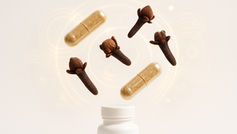 Cloves bud and Cloves capsules float above a white bottle against a light patterned background, suggesting a blend of natural and modern remedies.