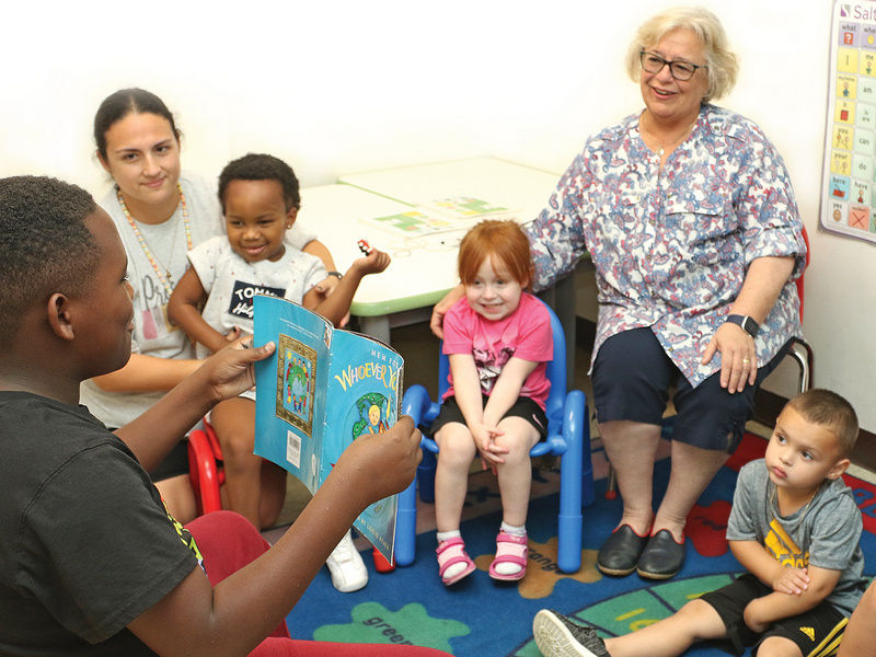 Adelen listens to a fellow student reading a book